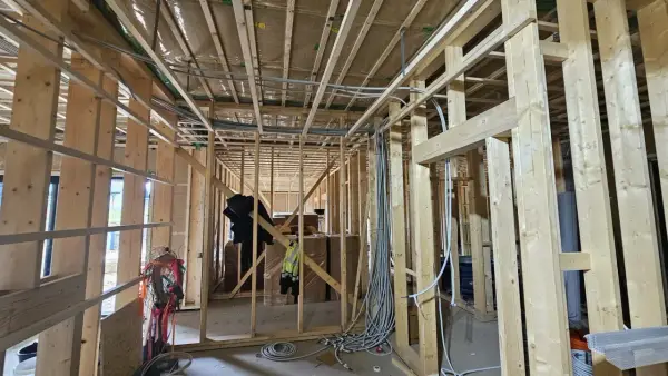 Widok wnętrza domu drewnianego w budowie. Widoczna instalacja elektryczna, drewniane ściany i stropy. Przepisy dotyczące instalacji elektrycznej w domach drewnianych są kluczowe dla bezpieczeństwa.